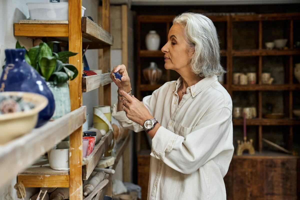 A thoughtful mature woman organizing her artistic workspace with creative passion in a serene studio