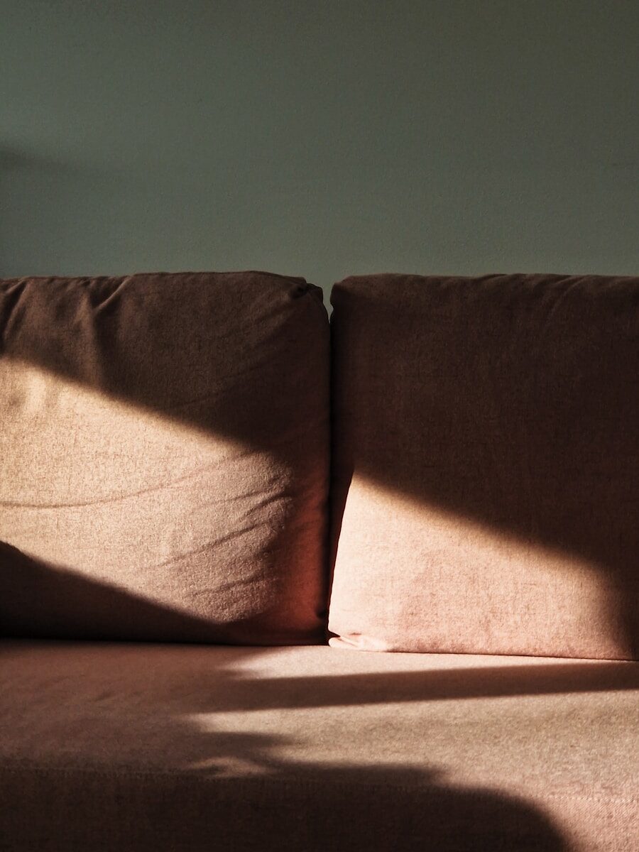 A brown couch with two pillows on top of it